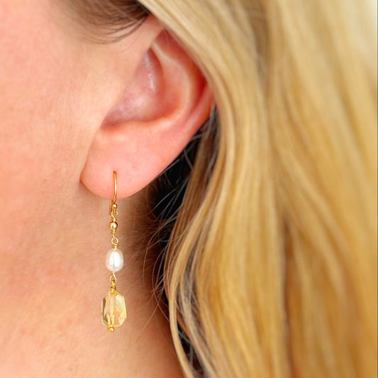 close up of a person wearing a 14k gold filled dangle earring with a small pearl and faceted citrine drop.