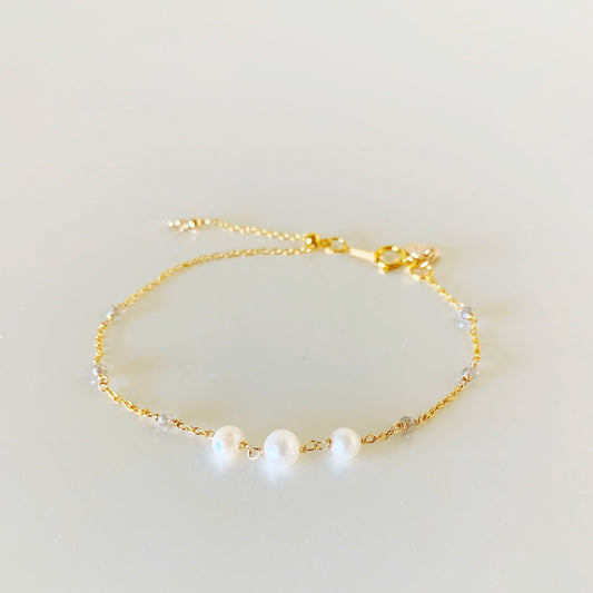 the westport bracelet by mermaids and madeleines is an adjustable chain designed bracelet with 3 freshwater pearls at the center of the bracelet and tiny microfaceted labradorite on the sides of the chain. there is a slide bead near the clasp to tighten the bracelet. this bracelet is facing forward and photographed on a flat white surface