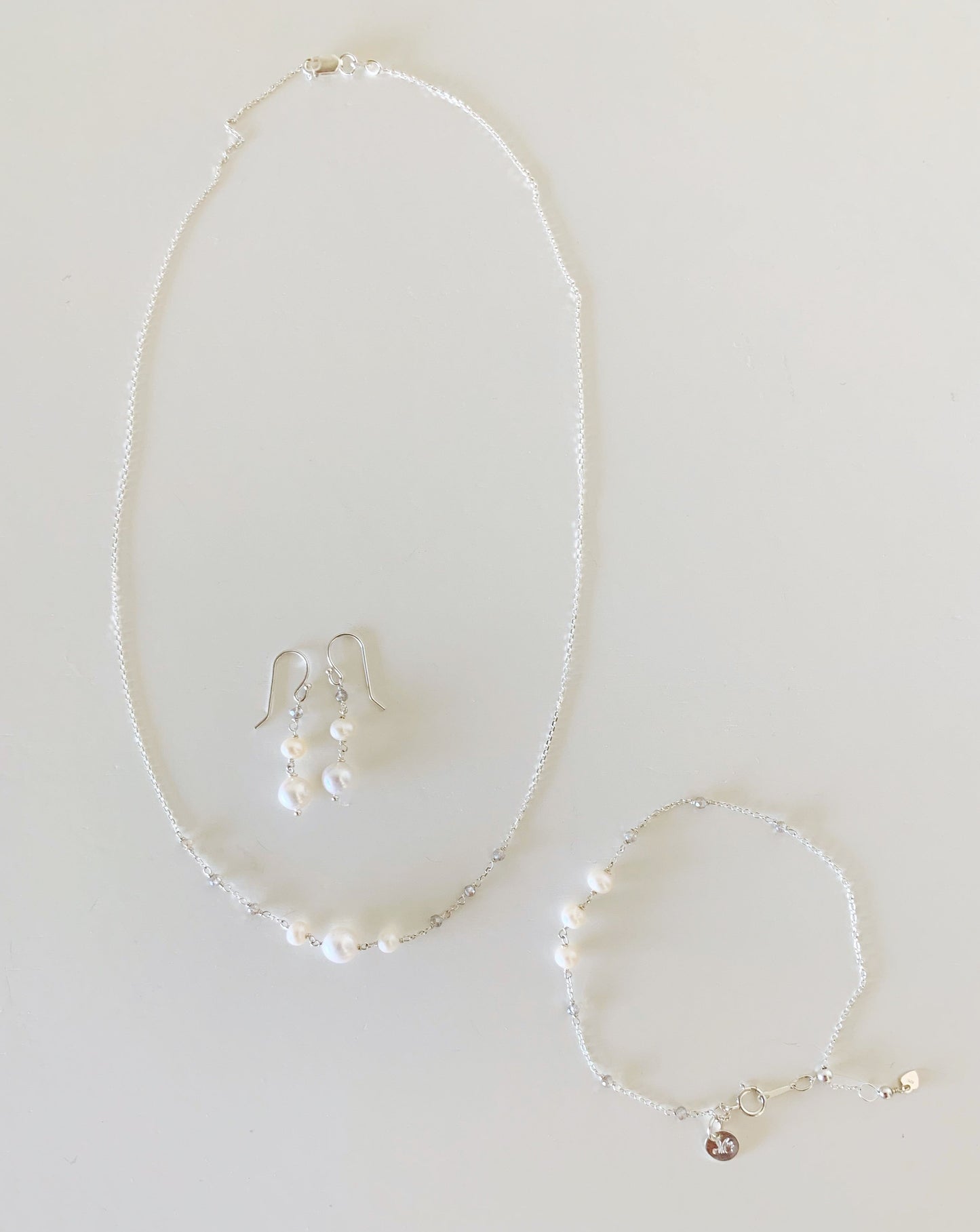 Westport  series by mermaids and madeleines is a necklace, bracelet and earrings created with freshwater pearl and labradorite gems on sterling silver chain. this  series is photographed on a white surface