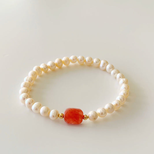 the you're a gem rhodochrosite stretch bracelet by mermaids and madeleines is designed with a flat rectangle rhodochrosite bead at the center with 14k gold filled beads and surrounded with freshwater pearls. this bracelet is photographed on a white surface