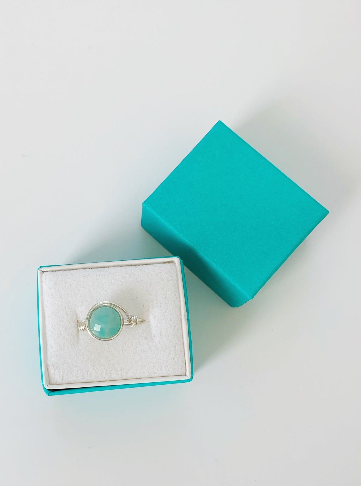 Mermaids and Madeleines Captiva sterling silver wire wrapped ring with amazonite gem at the center is photographed here in a teal gift box on a white surface