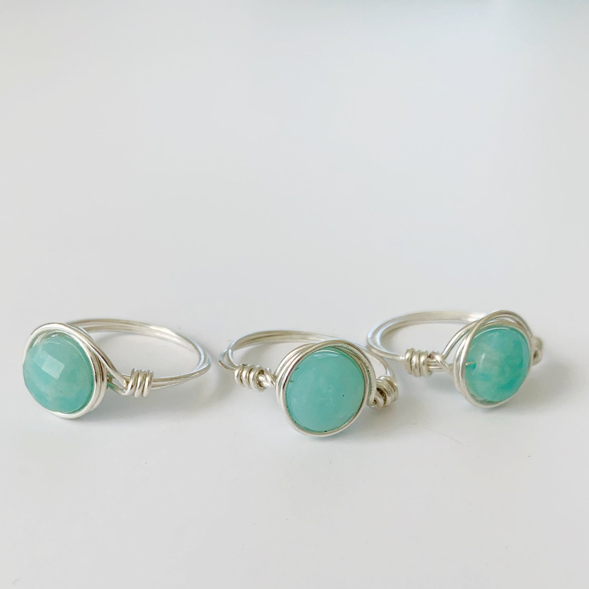 Captiva Rings by Mermaids and Madeleines are wire wrapped rings in sterling silver with amazonite gems at the center. There are 3 rings photographed here on a white surface