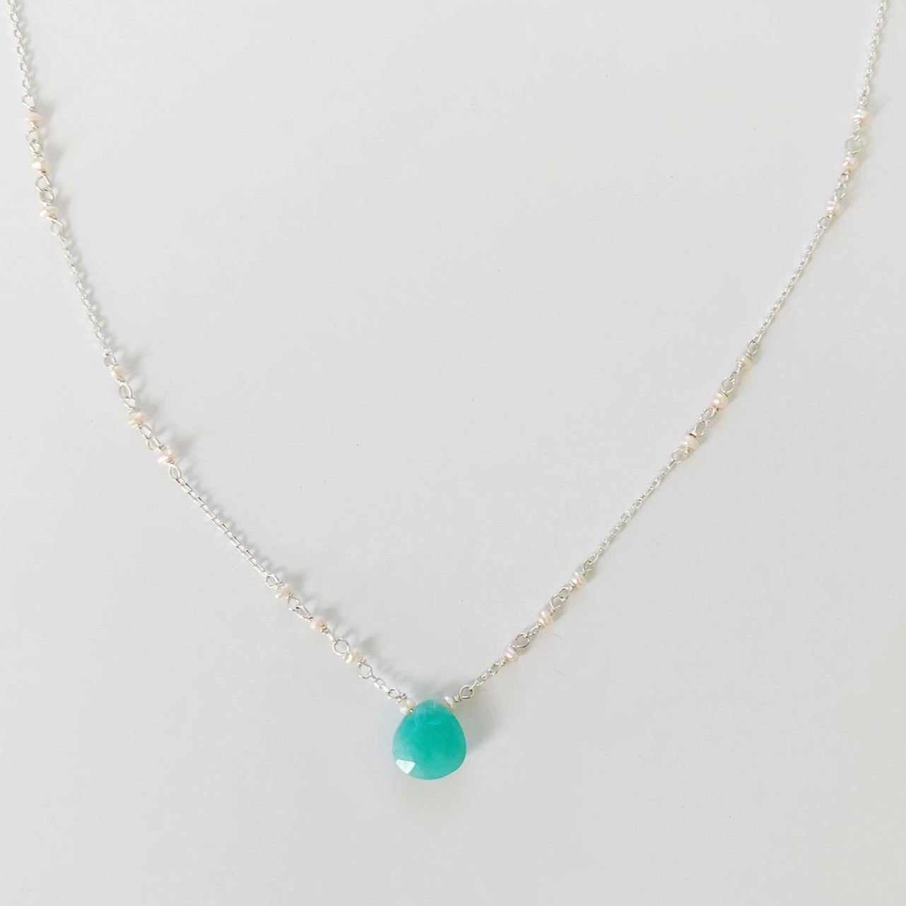 Island Air Necklace in sterling silver by mermaids and madeleines is created in with an amazonite gem at the center and tiny freshwater pearls in the chain. This necklace is pictured over a white background