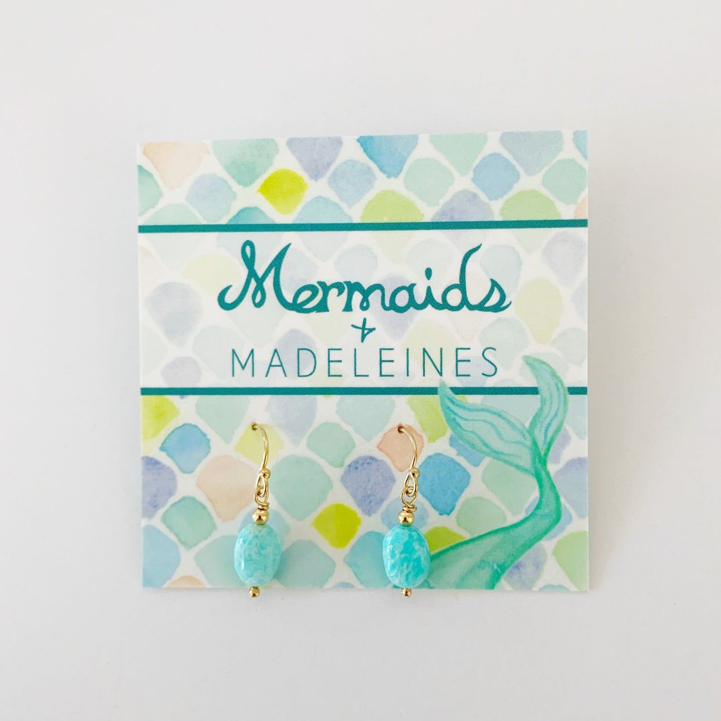 The laguna earrings in 14k gold filled. This pair is created with 14k gold filled beads and findings and bright aqua oval shaped beads. This pair is pictured on a mermaids and madeleines earring card and photographed on a white background