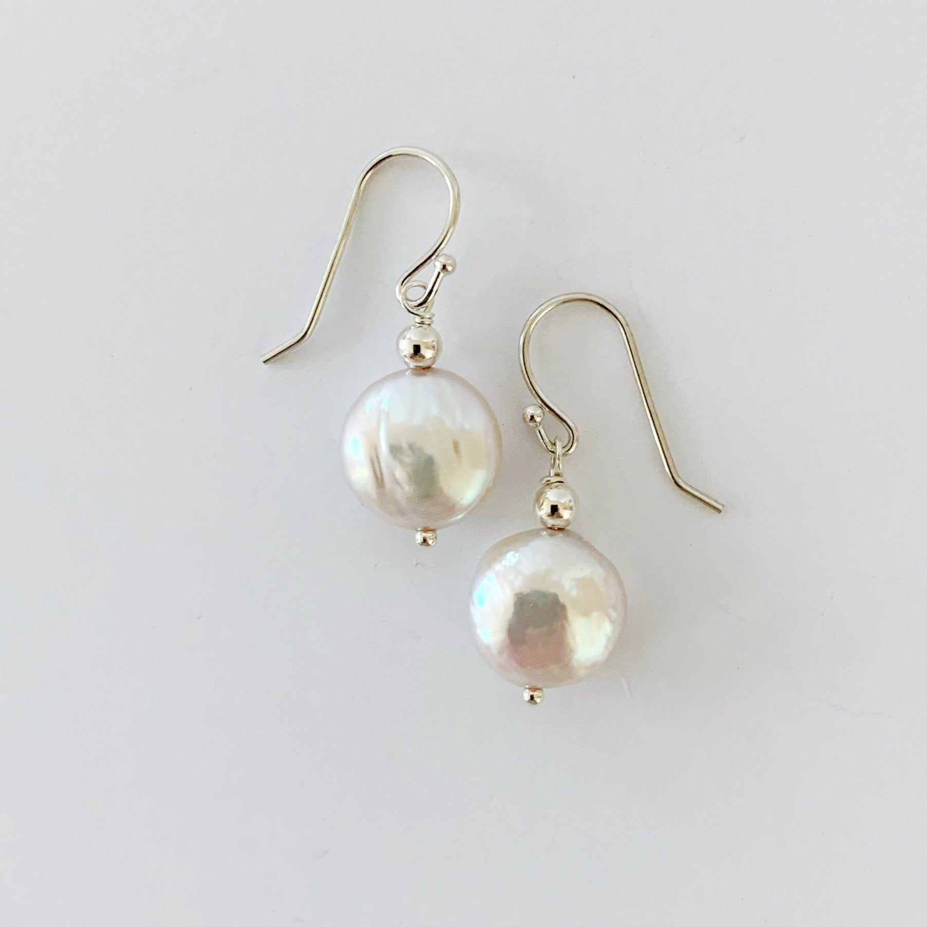 Newport earrings in sterling silver. This pair of earrings is created with sterling silver beads and earring findings with iridescent freshwater coin pearls. This pair is photographed on a white background