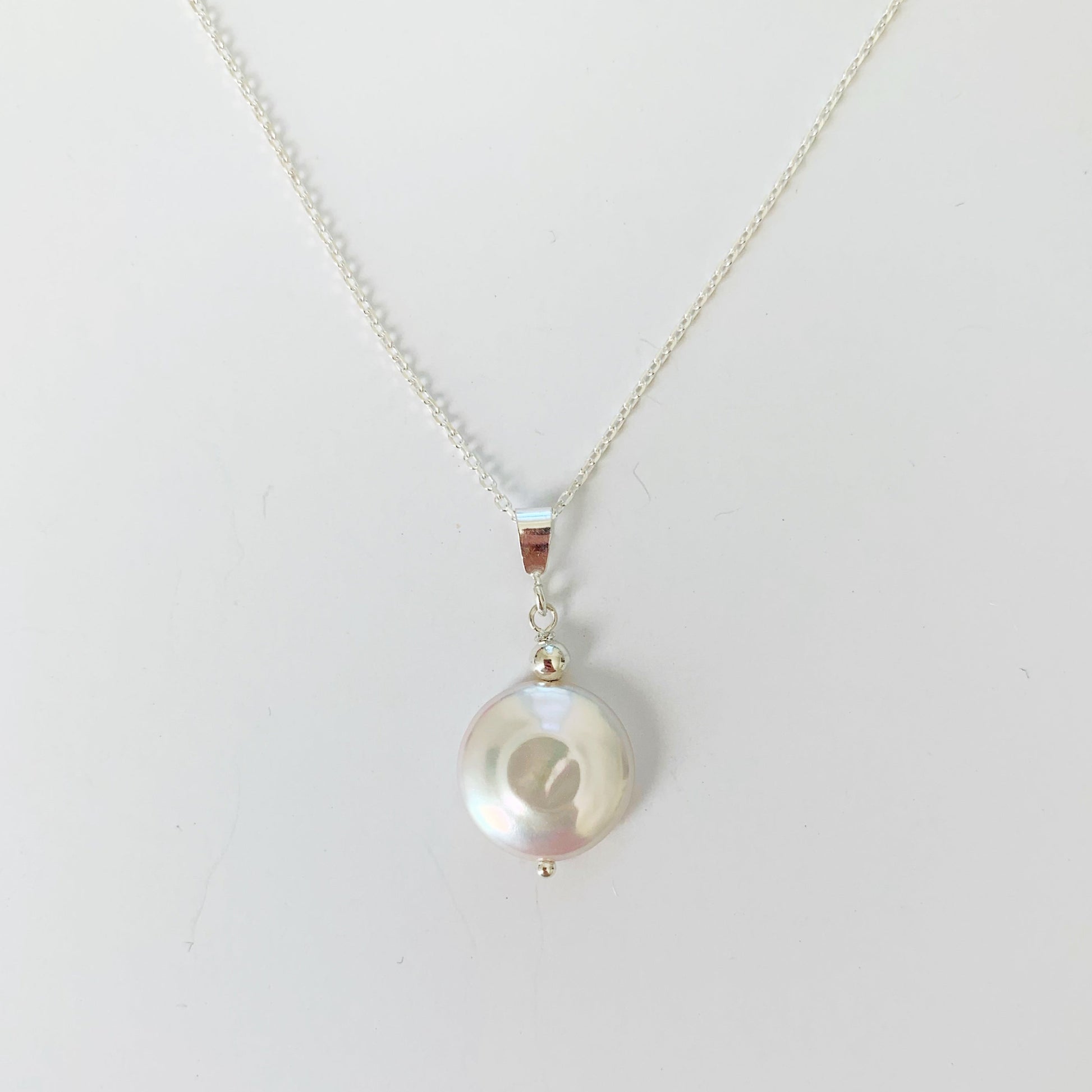 Newport Gala pendant in sterling silver by mermaids and madeleines is a large freshwater coin pearl pendant on sterling chain with silver findings. this one is pictured on a white surface