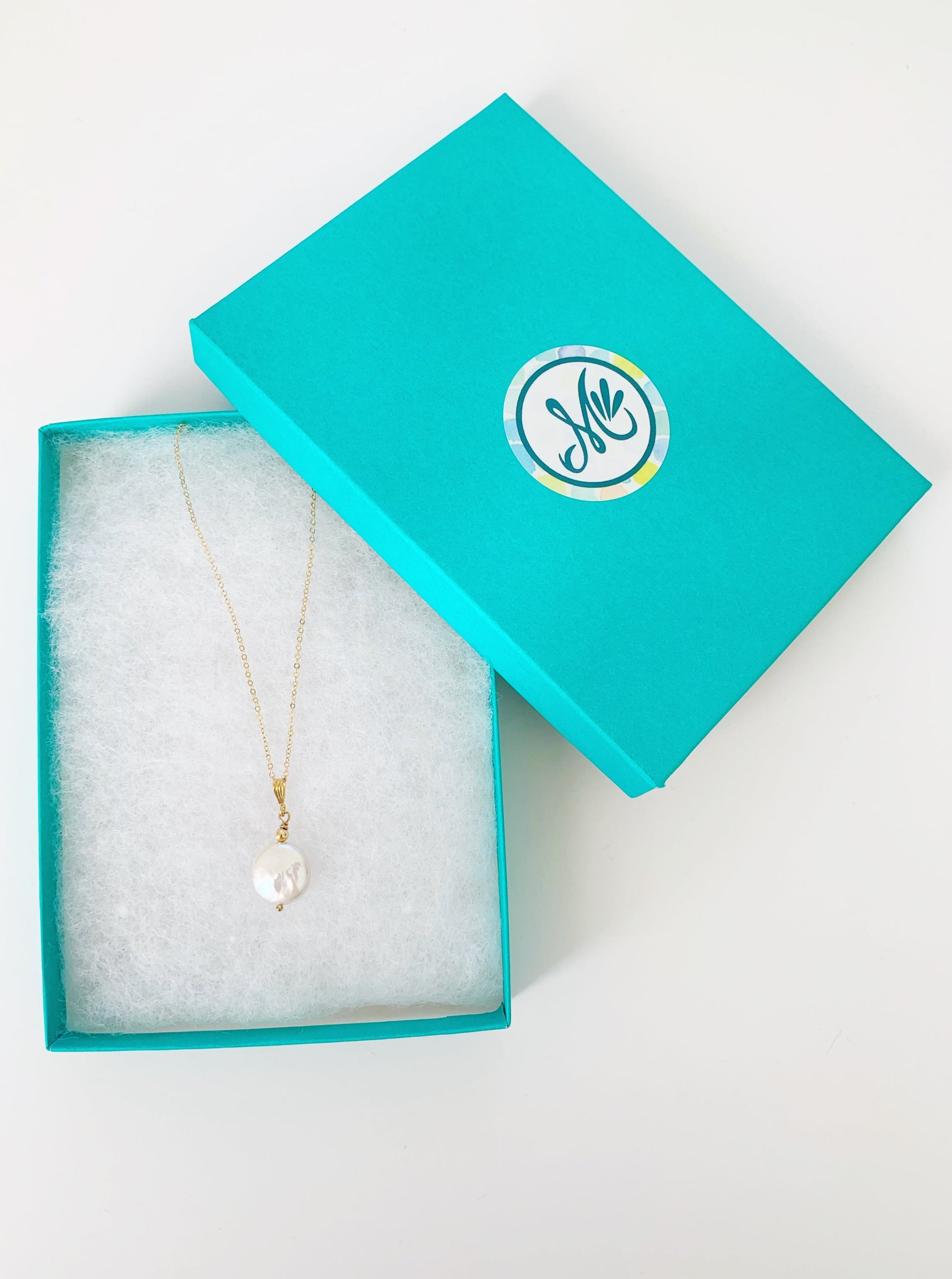 Newport Gala necklace in 14k gold filled is a large freshwater coin pearl pendant. this one is photographed in a teal gift box on a white surface