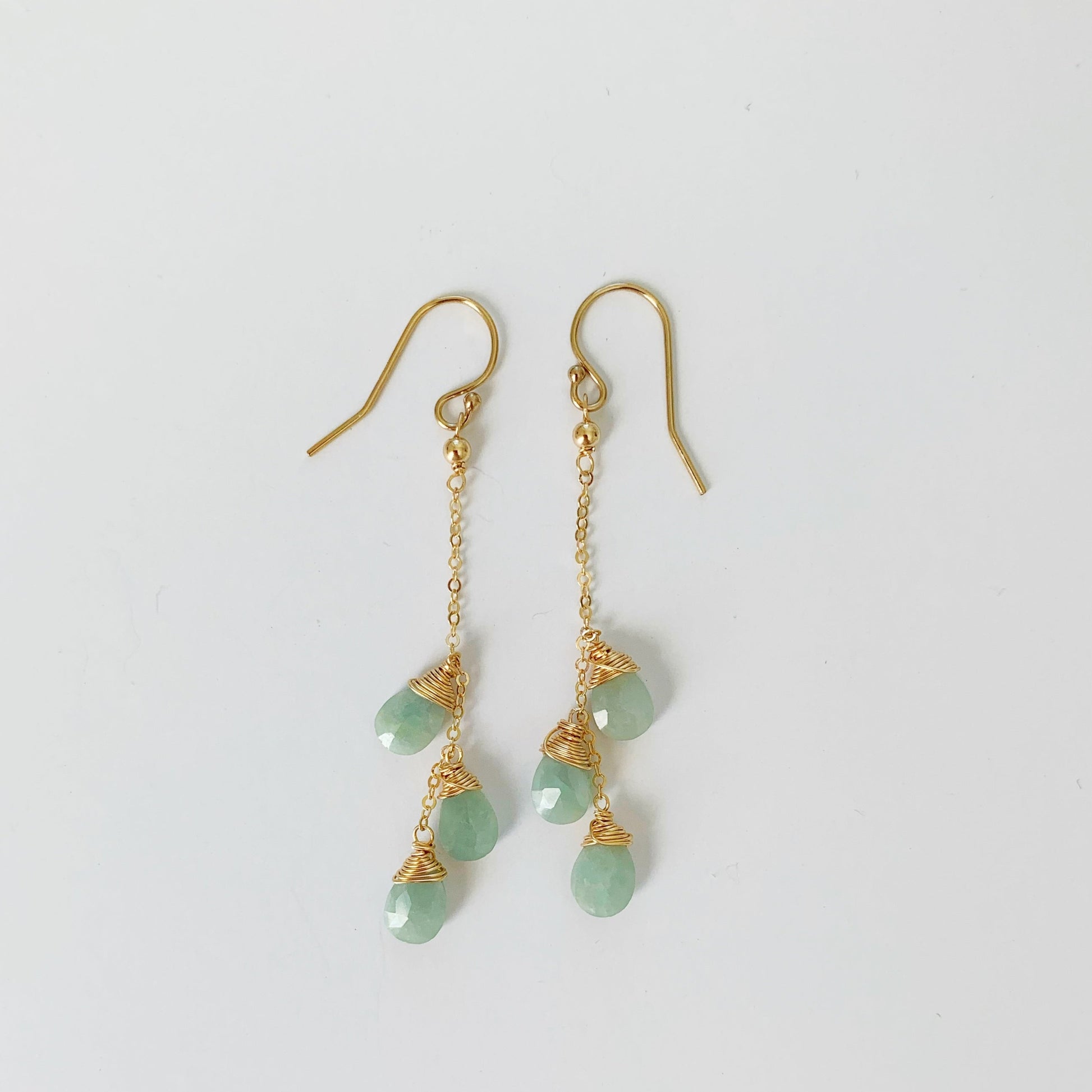 Raindrop aquamarine and 14k gold filled wire wrapped linear earrings by mermaids and madeleines. this pair is pictured on a white surface