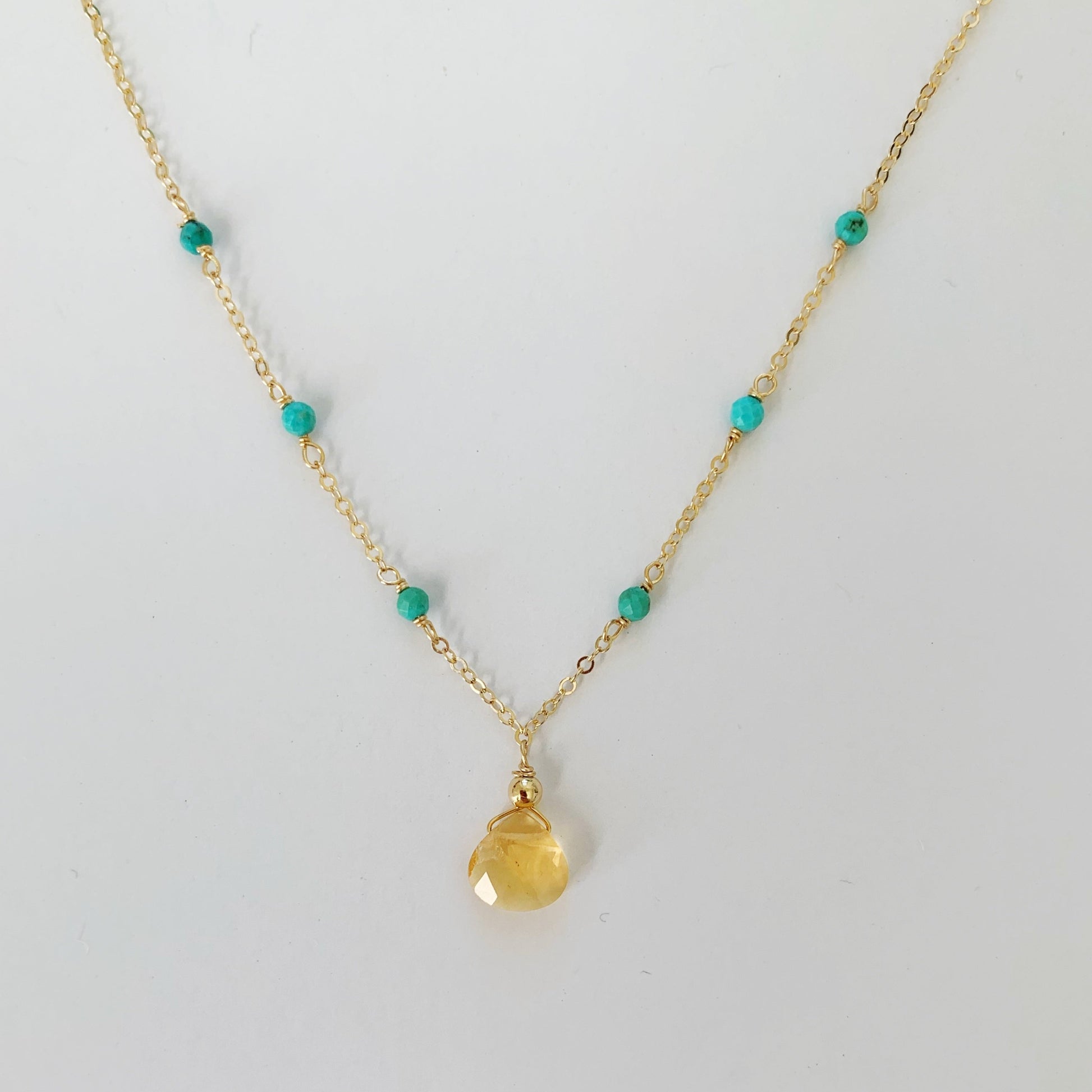 Ray of Sunshine Necklace by mermaids and madeleines is a dainty necklace featuring a yellow citrine drop and natural turquoise on 14k gold filled chain. this necklace is photographed on a white surface