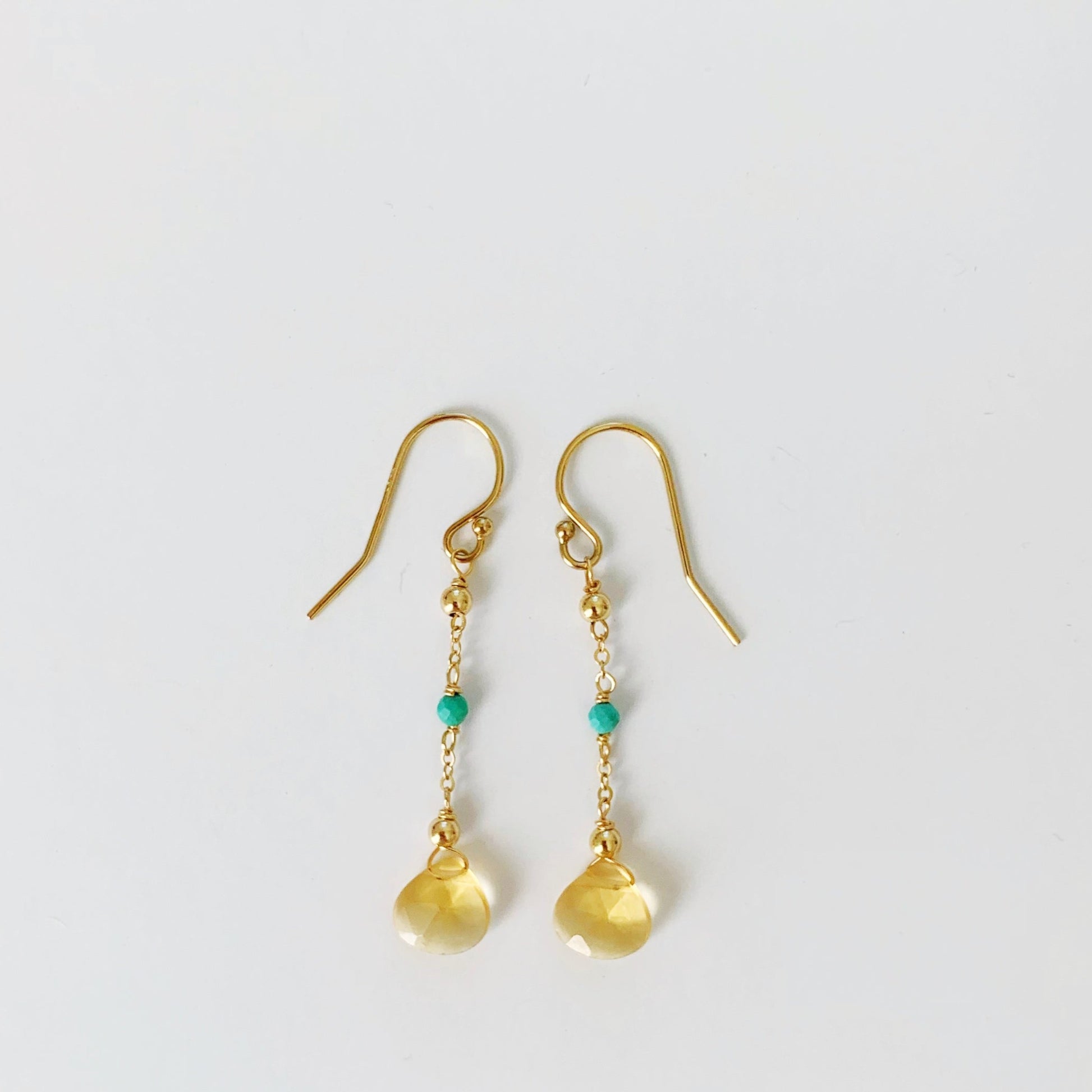 Ray of sunshine earrings by mermaids and madeleines are linear earrings with a yellow citrine drop and natural turquoise on 14k gold filled chain and findings. this pair is photographed on a white background