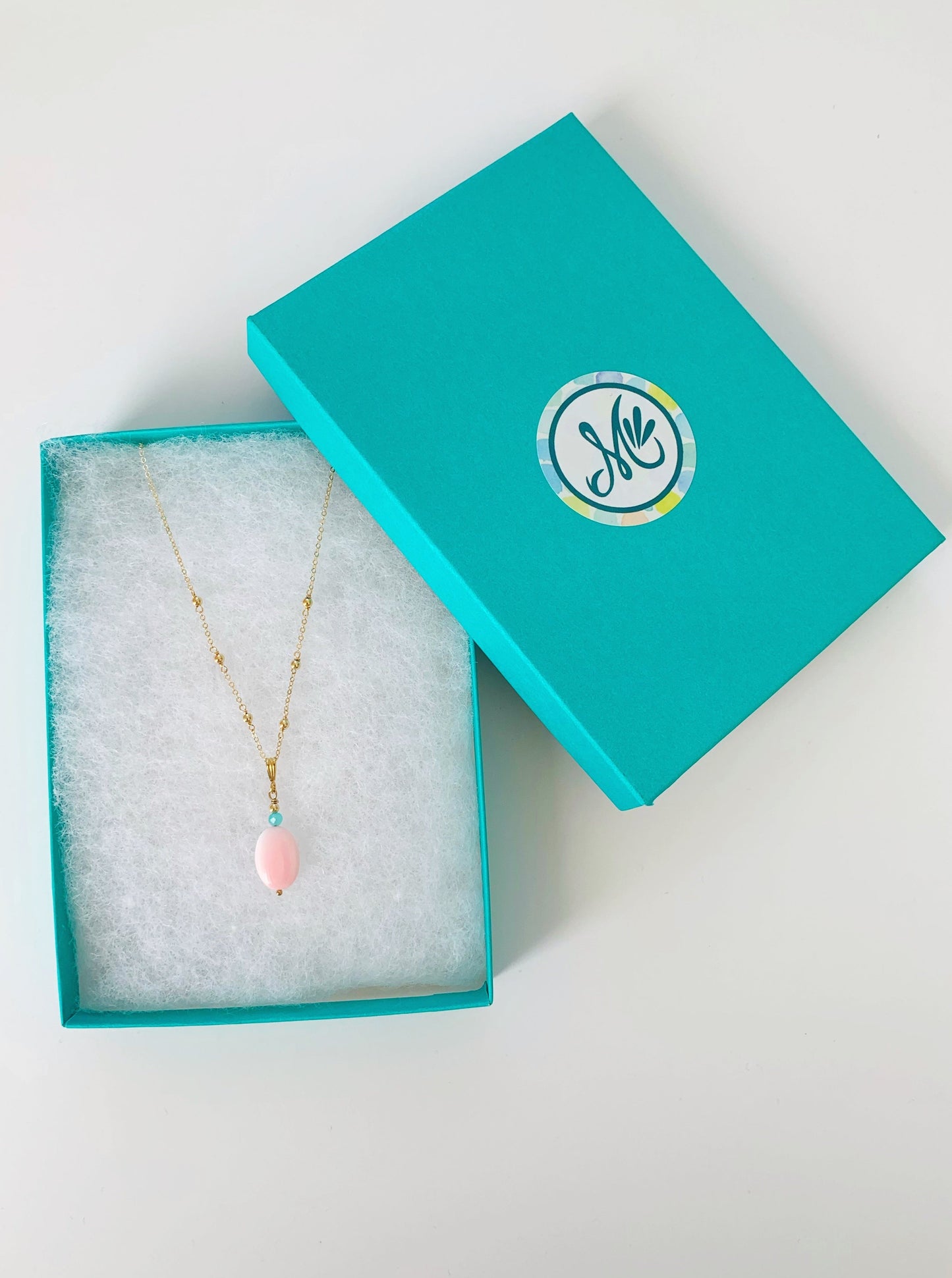 the sanibel necklace photographed in a teal gift box on a white surface