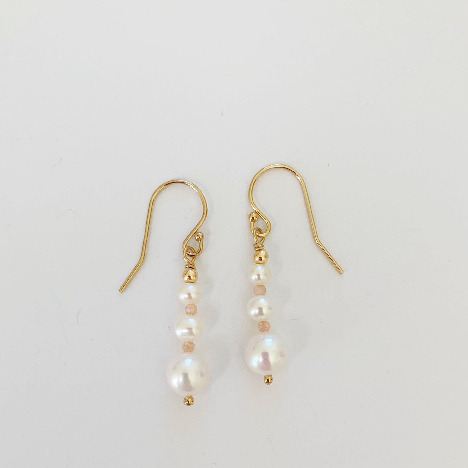 Barrington earrings by mermaids and madeleines are freshwater pearl linear drop earrings with peach moonstone and 14k gold filled findings. this pair is pictured on a white background