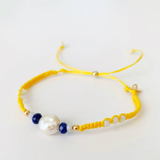 The bristol macrame bracelet in color buttercup yellow by mermaids and madeleines is an adjustable friendship bracelet with freshwater coin pearl, semiprecious beads and a 14k gold filled slide bead clasp. this bracelet is photographed on a white background