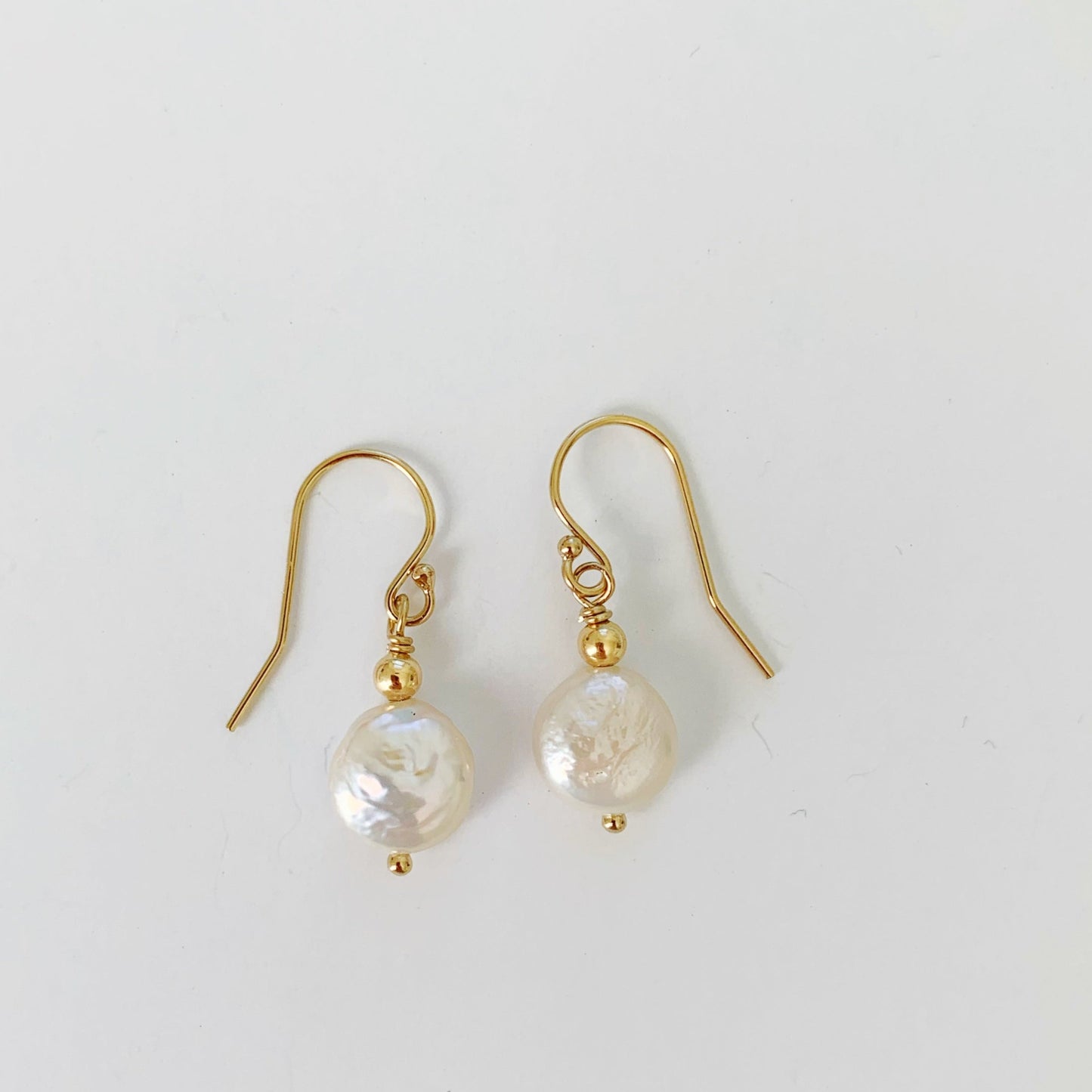 Newport Pearl Earrings by Mermaids and Madeleines are small freshwater coin pearls with 14k gold filled beads and findings. these ones are photographed on a white surface
