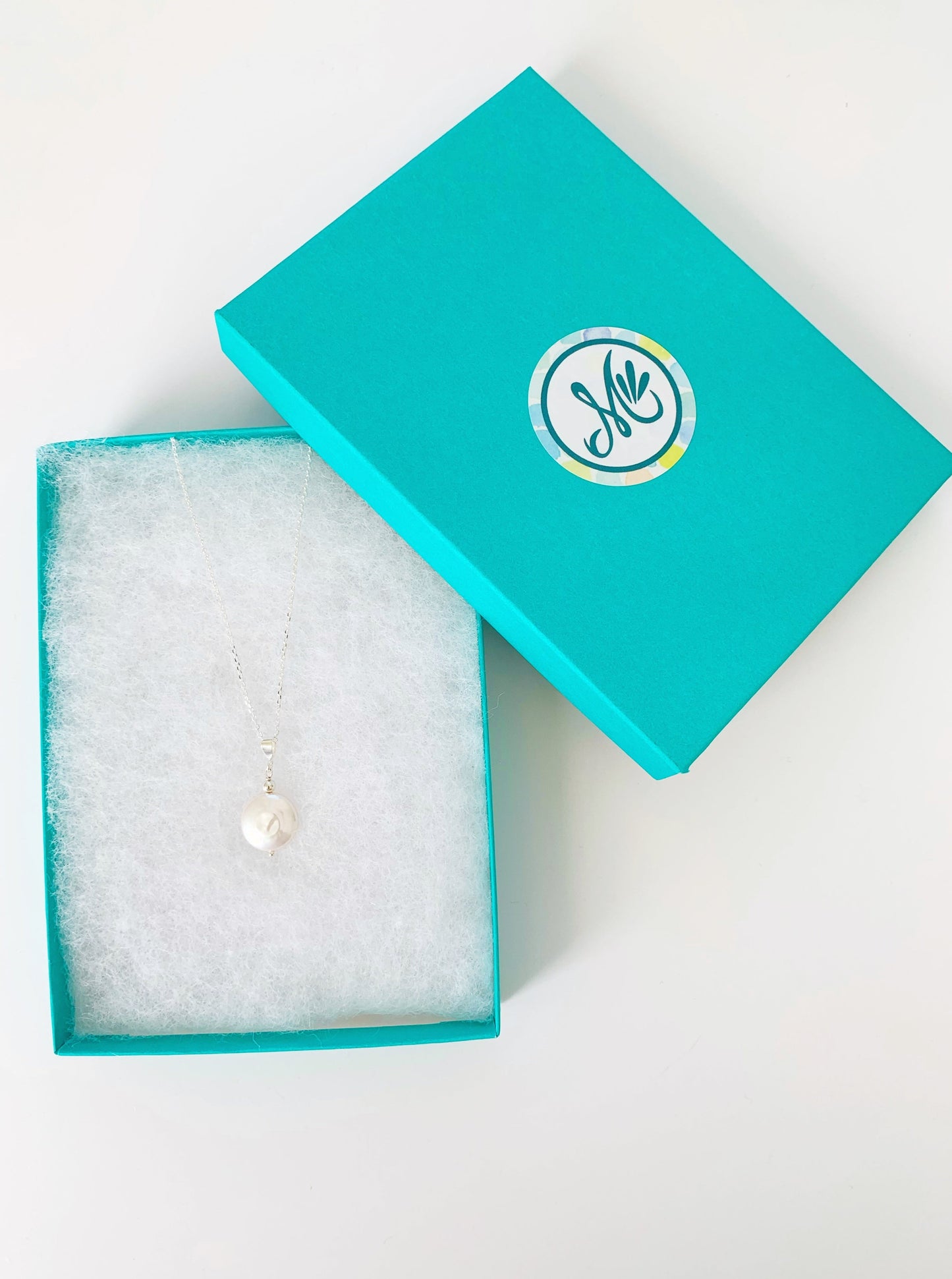 Newport Gala Large Coin Pearl necklace in sterling silver pictured here in a teal gift box on a white surface