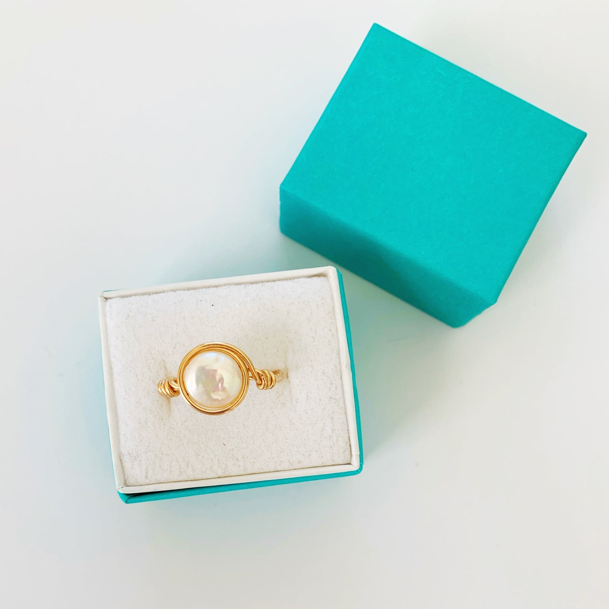 Newport pearl wire wrapped ring with freshwater coin pearl and 14k gold filled wire. pictured here in a teal ring gift box on a white surface