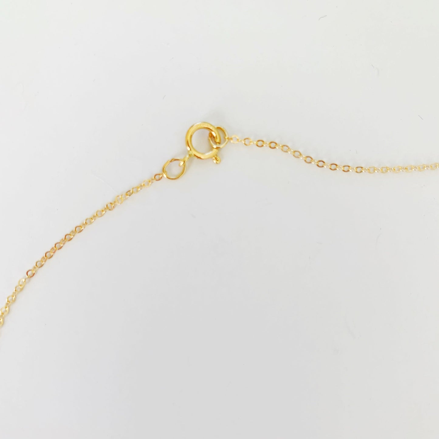 The back of the newport pearl necklace in gold filled is clasped with a spring ring photographed here on a white surface
