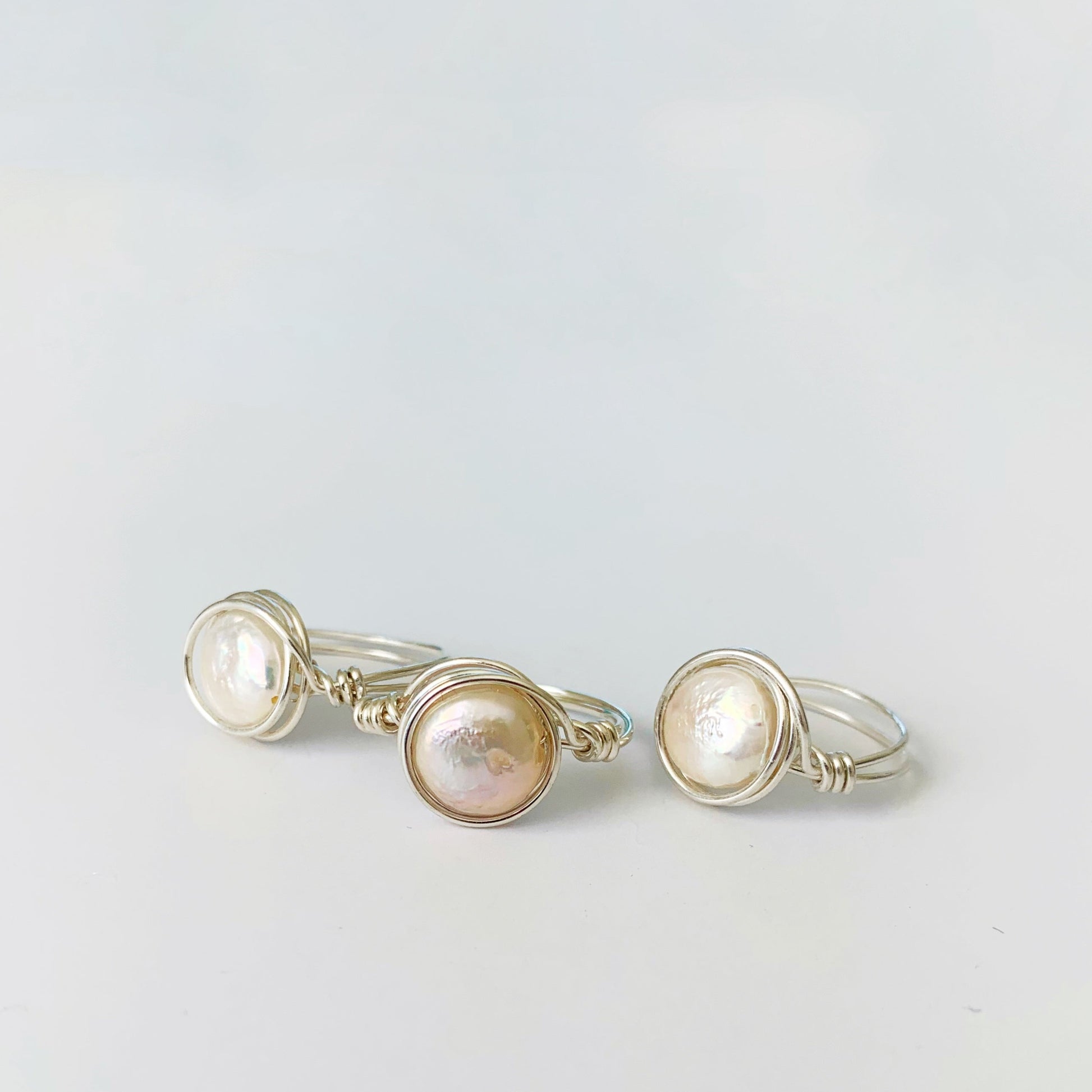 Newport Pearl wire wrapped rings in sterling silver and freshwater coin pearl. pictured here 3 rings on a white surface