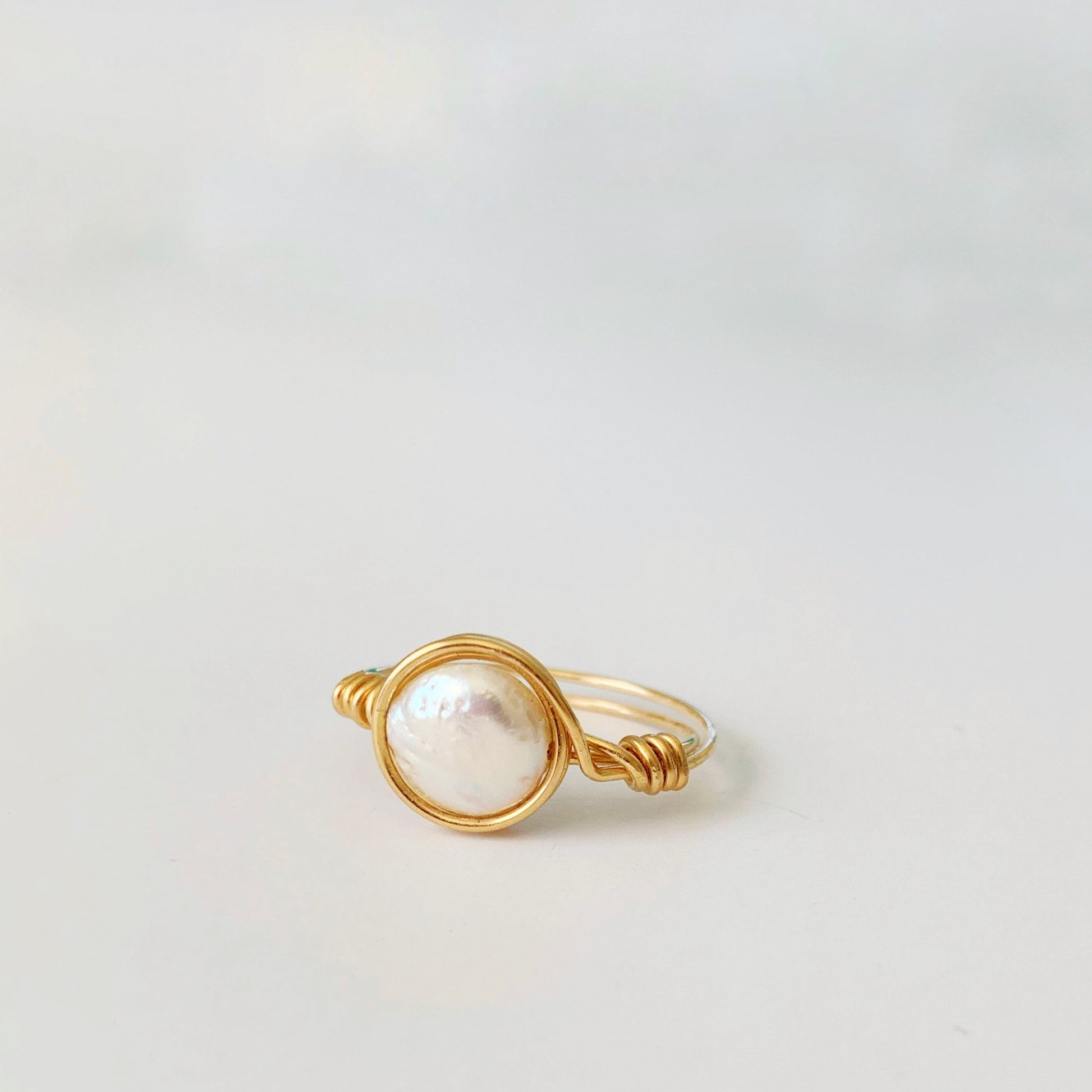 Newport pearl ring by mermaids and madeleines is a 14k gold filled wire wrapped ring with a small coin pearl. this one is photographed on a white surface