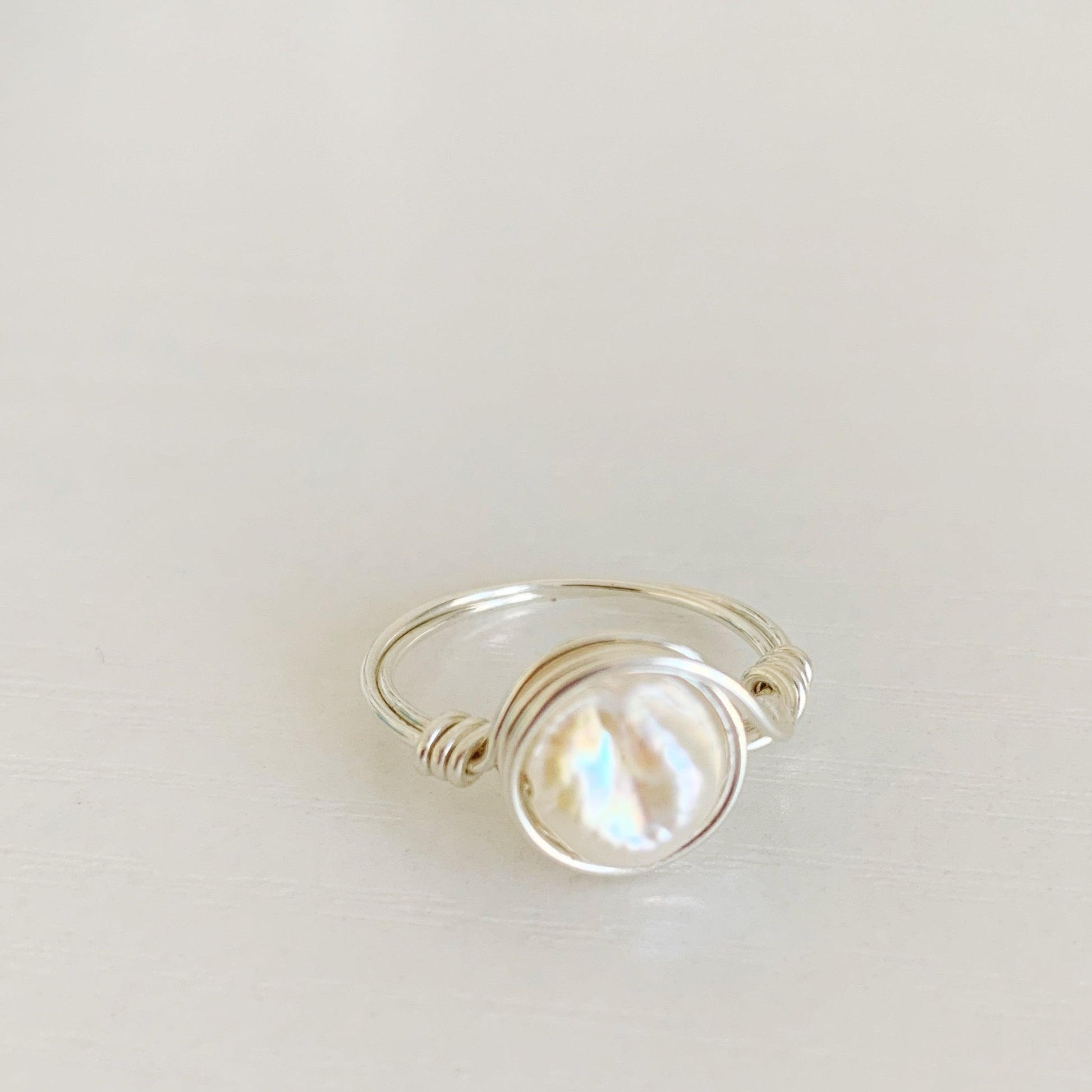 Newport Pearl Ring in sterling silver by mermaids and madeleines. this ring features a freshwater coin pearl and sterling silver wire. The ring is a wire wrap style making it simple and artful. this ring is photographed from a slight angle side view on a white surface