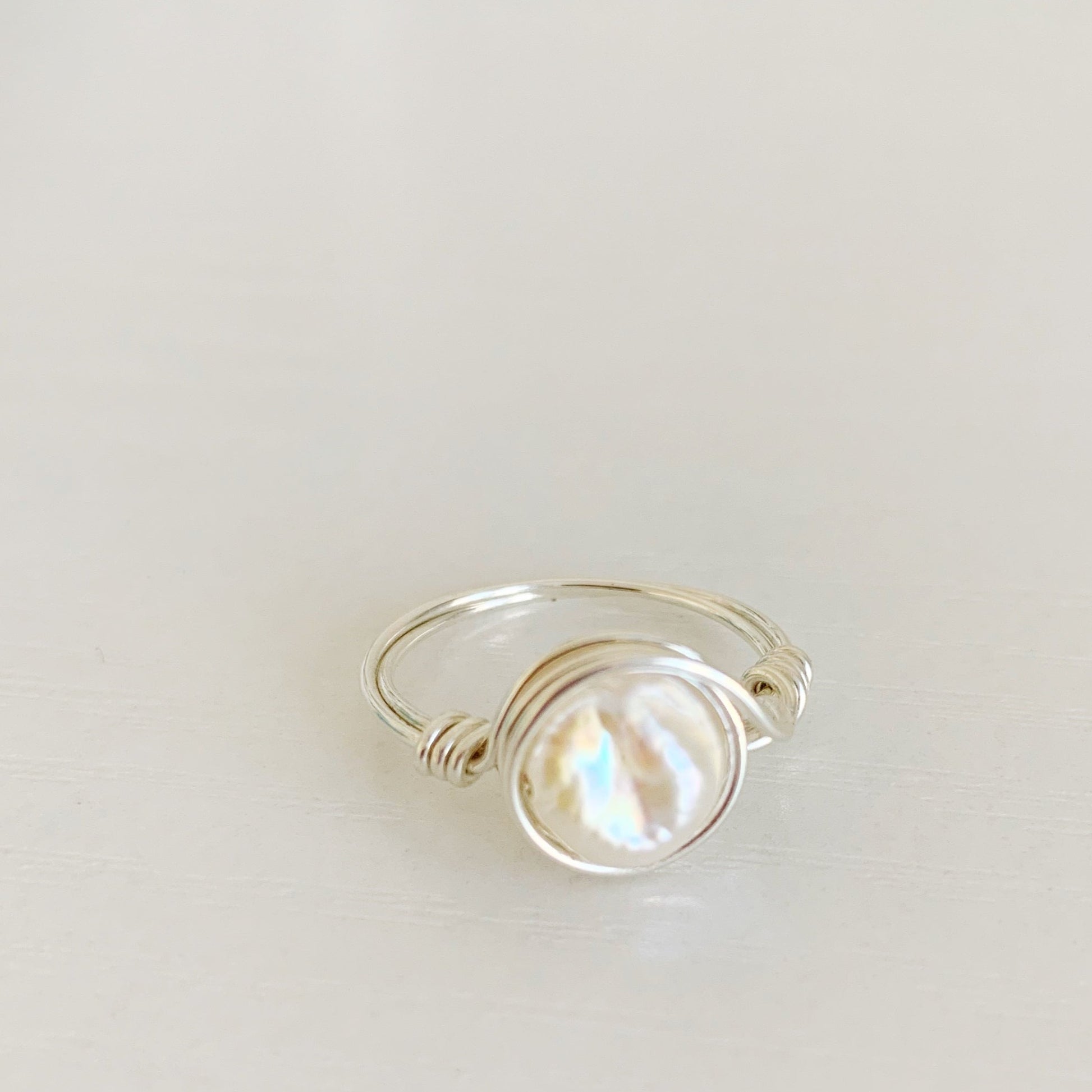 Newport Pearl Ring in sterling silver by mermaids and madeleines. this ring features a freshwater coin pearl and sterling silver wire. The ring is a wire wrap style making it simple and artful. this ring is photographed from a slight angle side view on a white surface