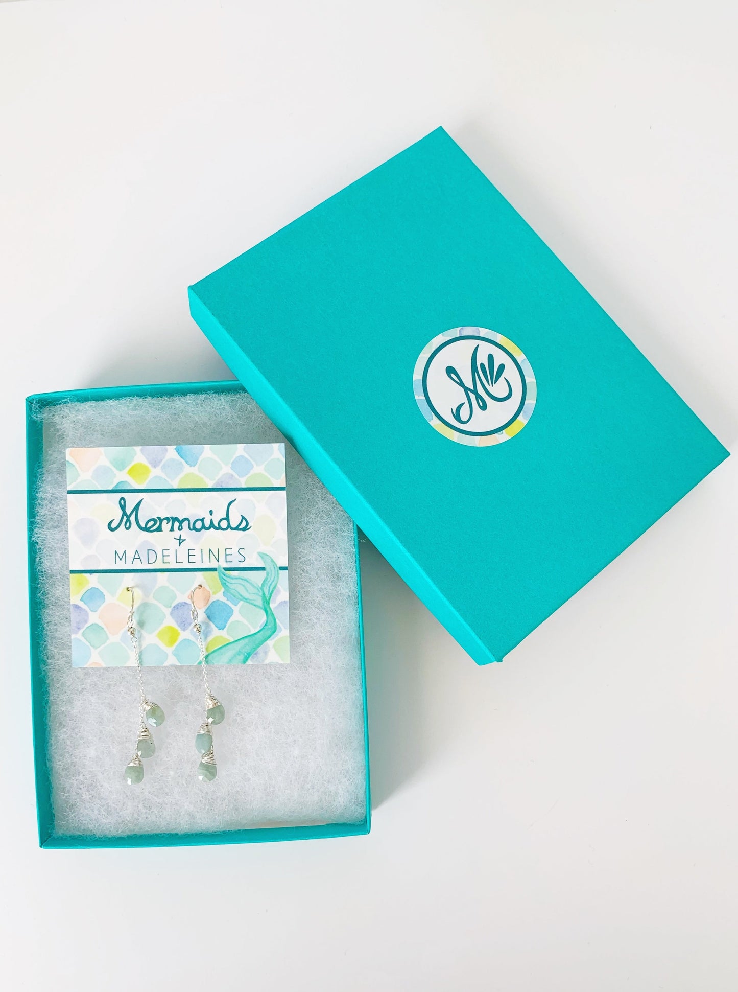 Raindrop earrings in sterling silver with aquamarine, photographed here in a teal gift box on a white surface