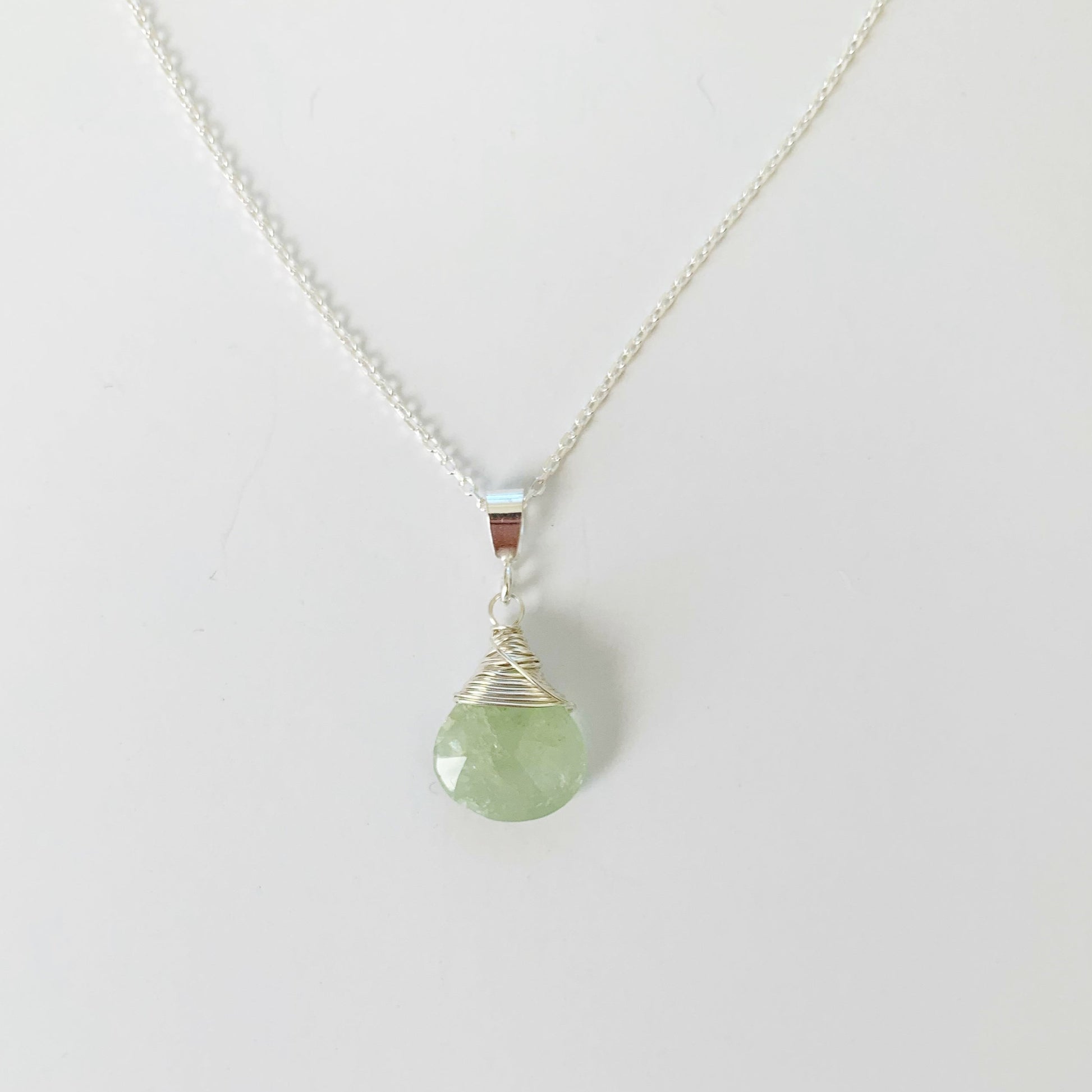 Raindrop necklace by mermaids and madeleines is a sterling silver wire wrapped pendant necklace with aquamarine. this necklace is photographed on a white surface