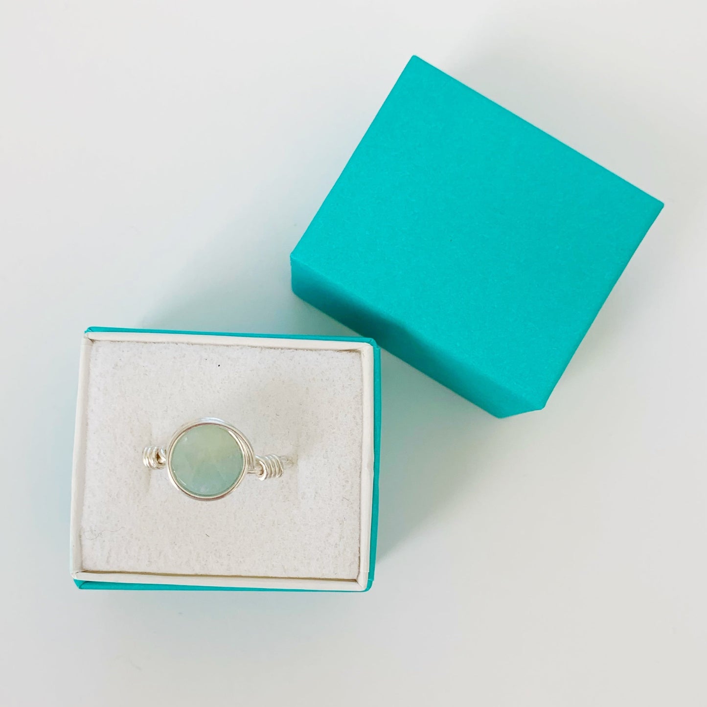 Raindrop ring in sterling silver with aquamarine pictured here in a teal ring box on a white surface