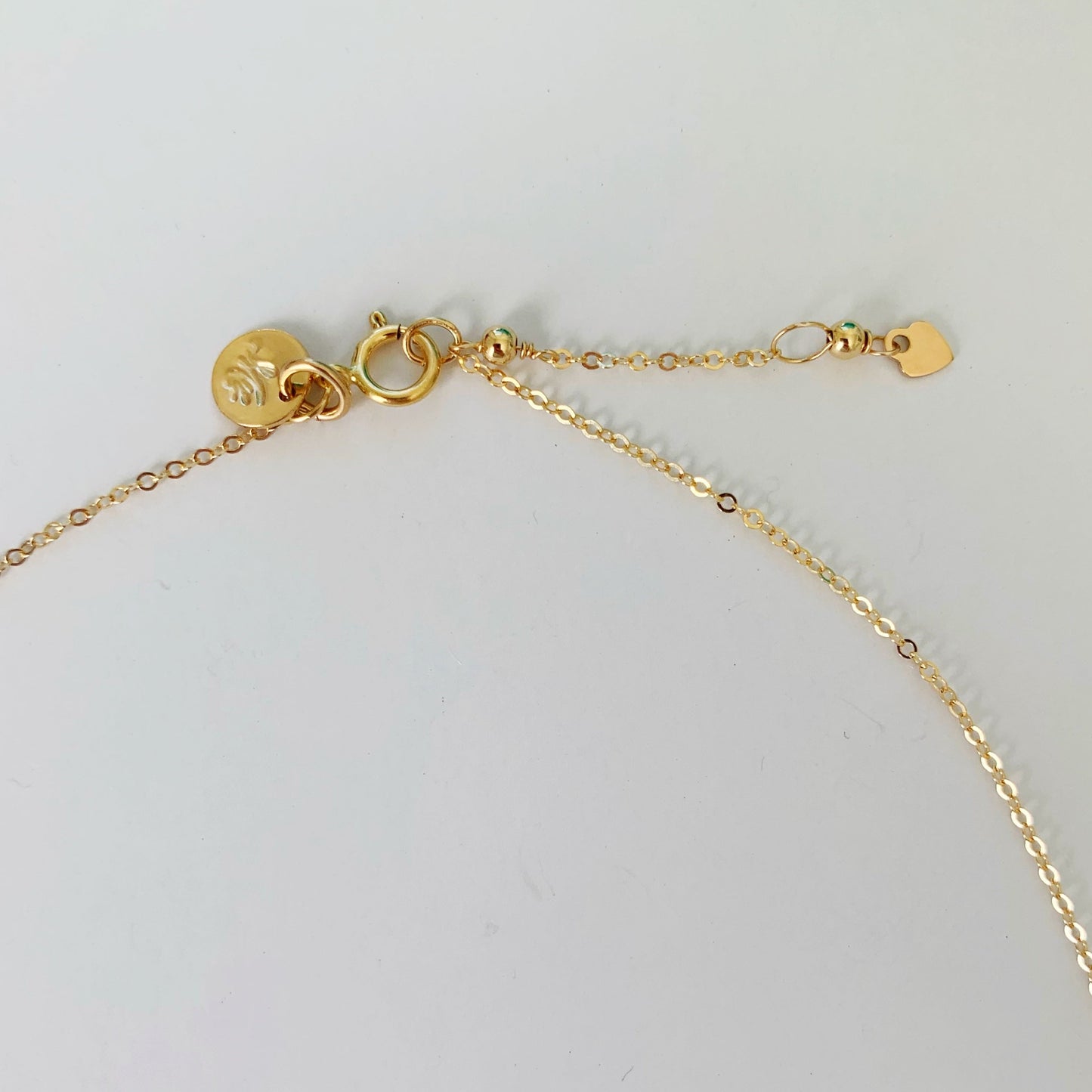 The sanibel necklace has a spring ring clasp and 1" extender chain at the back in 14k gold filled. pictured here on a white surface