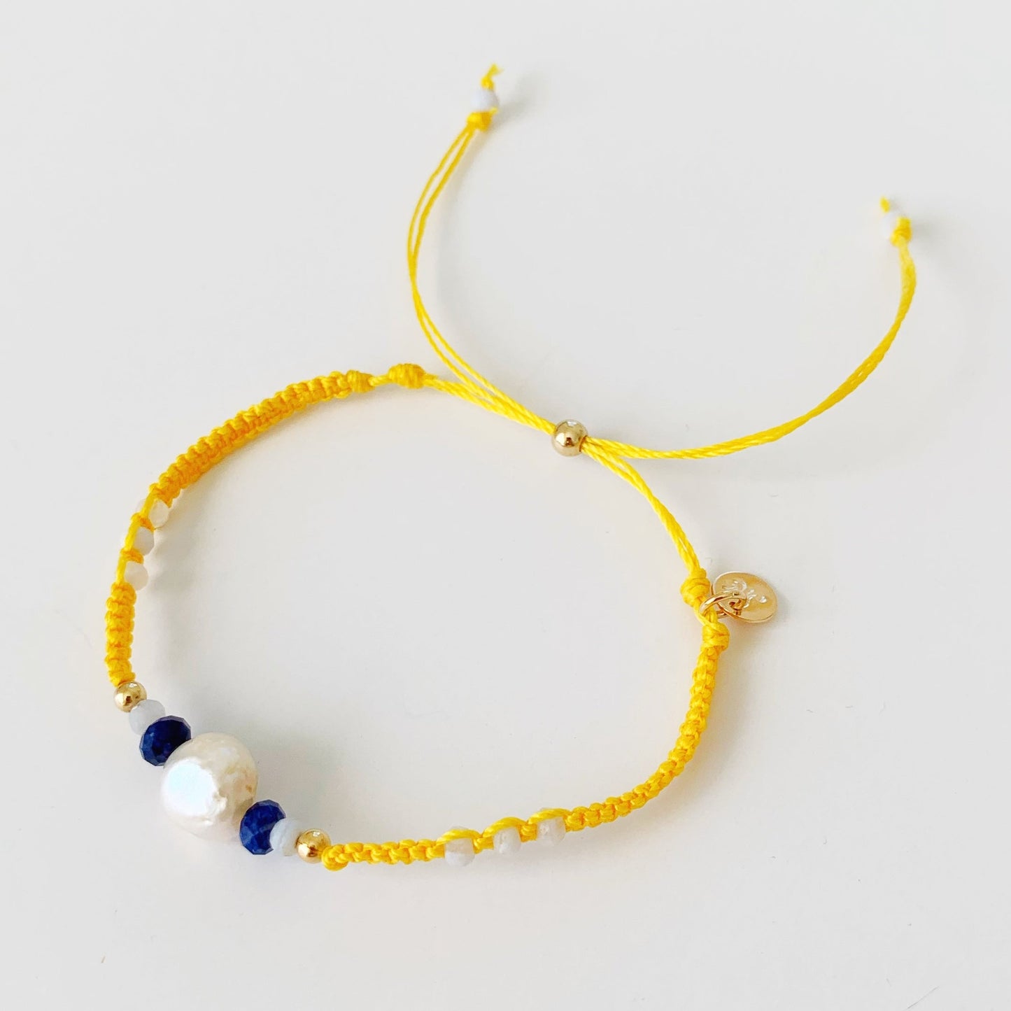 the yellow macrame bracelet is photographed from a top view over a white surface